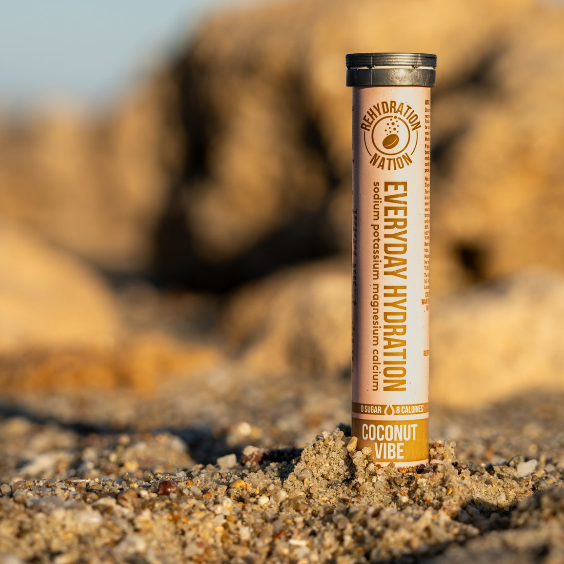 ehydration Nation Coconut Vibe hydration tablets – tube photographed on sand with a summer beach background
