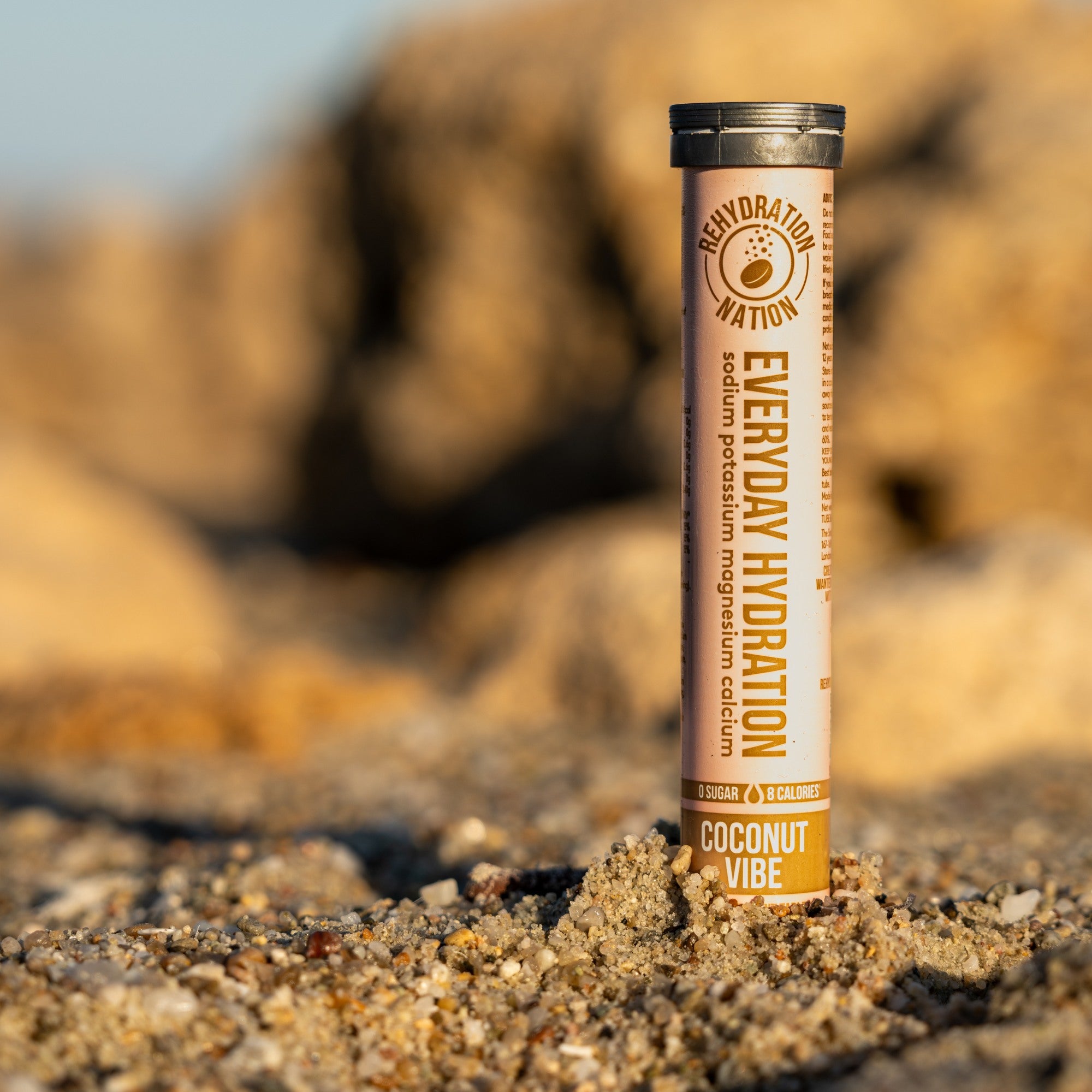 ehydration Nation Coconut Vibe hydration tablets – tube photographed on sand with a summer beach background