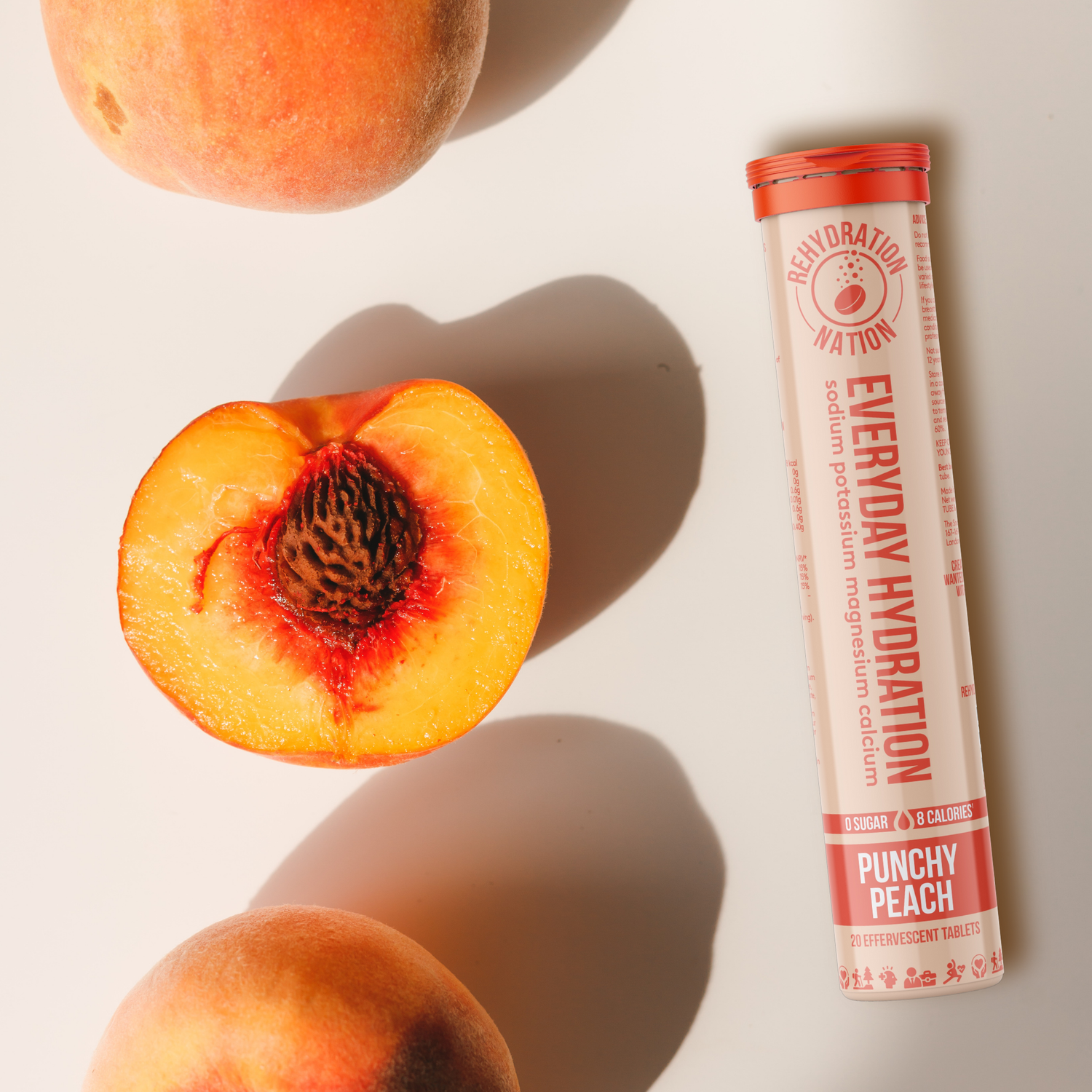 Tube of Everyday Hydration Punchy Peach flavor on a light background with peaches.