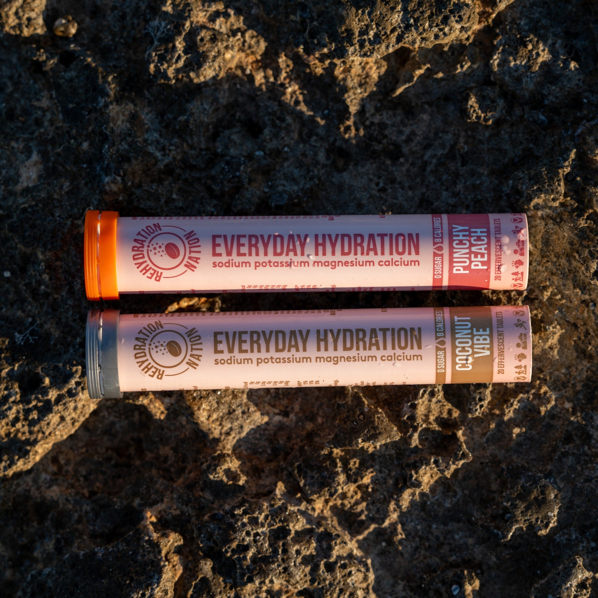 Rehydration Nation Punchy Peach and Coconut Vibe hydration tablets – flatlay photograph of two tubes placed on rock surface outdoors
